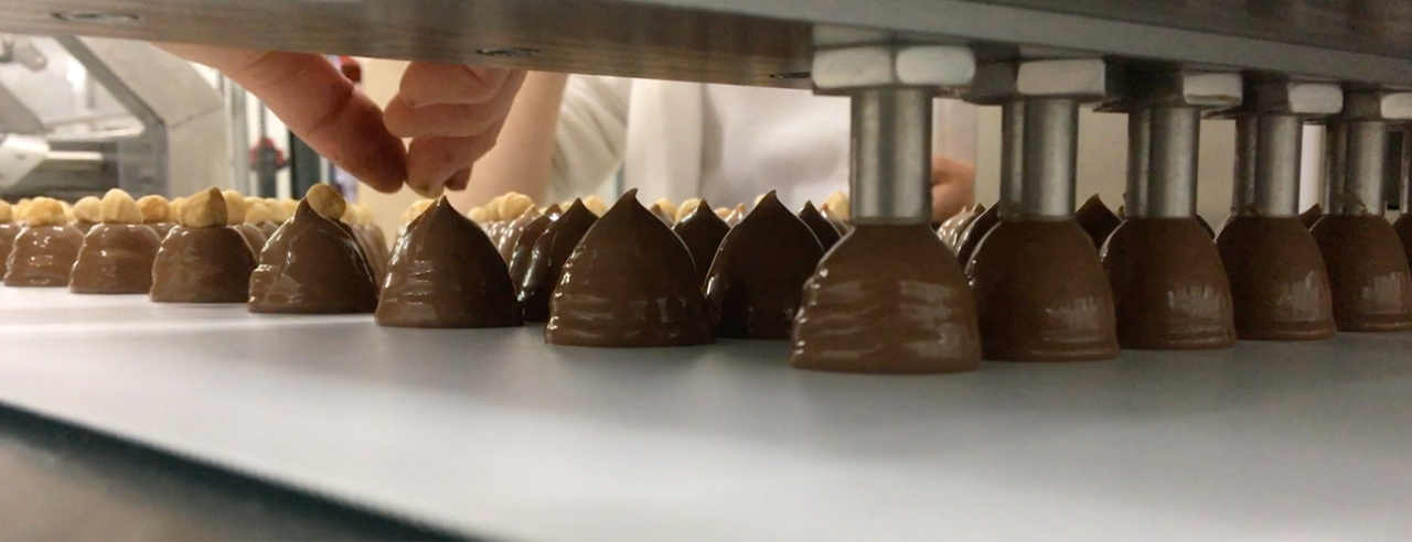 Ervaar de innovatie van Betec One Shot doseersystemen met de Boss 275. Deze tandwiel doseermachine maakt de eenstapsproductie van chocoladeproducten mogelijk, inclusief die met vullingen met een zachte kern. Uitgerust met bufferhoppers, verwisselbare doseerplaten en de mogelijkheid om zowel de chocoladeschil als de vulling tegelijkertijd in te spuiten, revolutioneert de Boss 275 de chocoladeproductie.