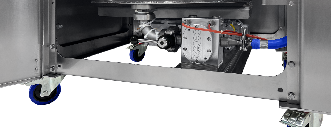 Binnenkant van de Aura WK 200 smelt- en werkketel voor chocoladeverwerking, met geïntegreerde Betec GP 200 chocoladepomp en aandrijfmotoren ingebouwd onderaan in het frame – een strak en hygiënisch ontwerp met eenvoudig onderhoud dankzij de toegankelijke zijdeuren.